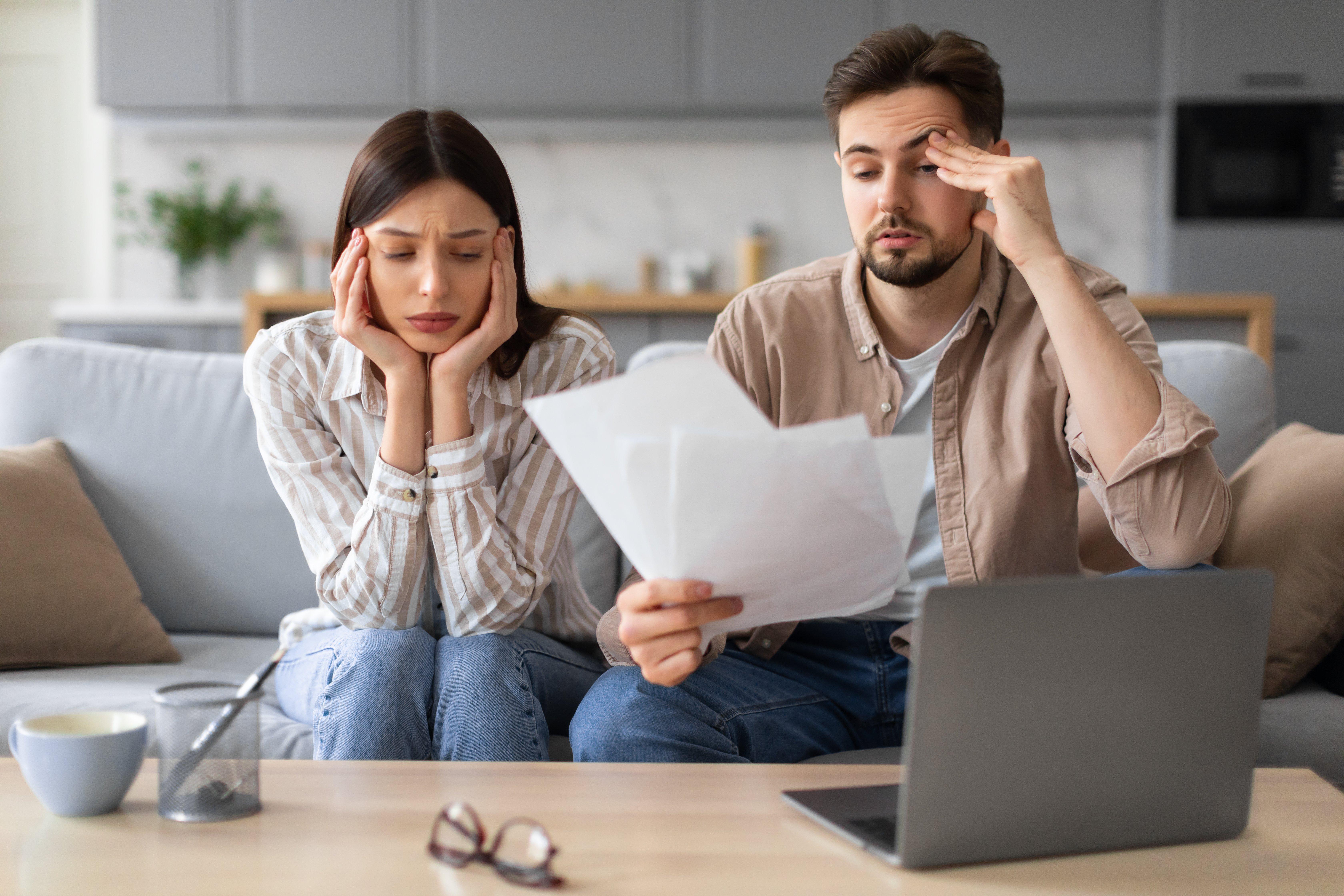 worried-european-couple-with-paperwork-laptop